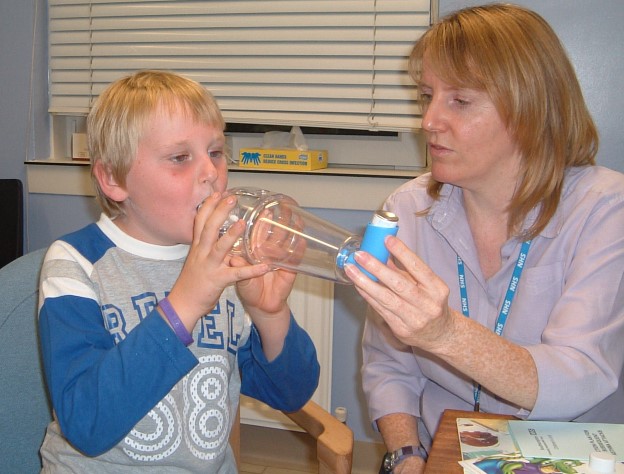 Older child begin given reliever inhaler using spacer with the help of an adult